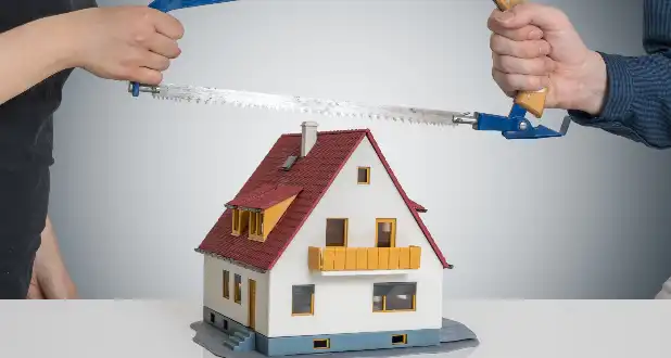 Image of a divorce house split; two people sawing a toy house.